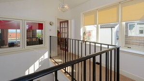 Una habitación amplia con techo alto, una araña y grandes ventanales que ofrecen vistas al exterior.