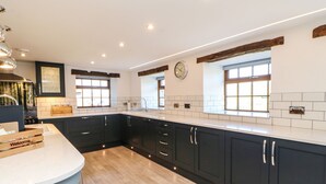 Une cuisine moderne avec des meubles de couleur sombre, un plan de travail en bois et un évier encastré.