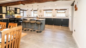 Une cuisine moderne dotée d’un îlot central, de tabourets de bar, de chaises en bois et d’une table à manger.