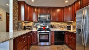 Una cocina moderna con armarios de madera oscura, electrodomésticos de acero inoxidable y un salpicadero de azulejos.