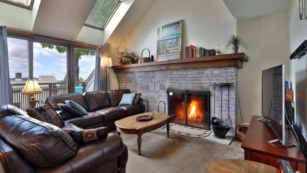 Una sala de estar acogedora con chimenea, sofá de cuero y televisor.