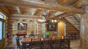A log cabin interior with a dining table, chairs, a chandelier, and a fireplace. - (67) El Capitan (3 Bedrooms Only) at The Redwoods In Yosemite (Yosemite National Park)