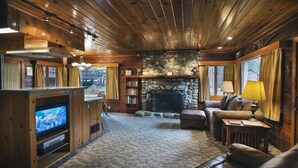 A cozy living room with a stone fireplace, wooden ceiling, and a television on a wooden stand. - (72) Sequoia (1 Bedroom Only) (Yosemite National Park)