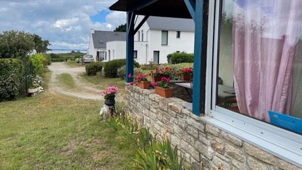 Une maison avec un mur en pierre, une véranda avec un toit bleu et des plantes en pot.