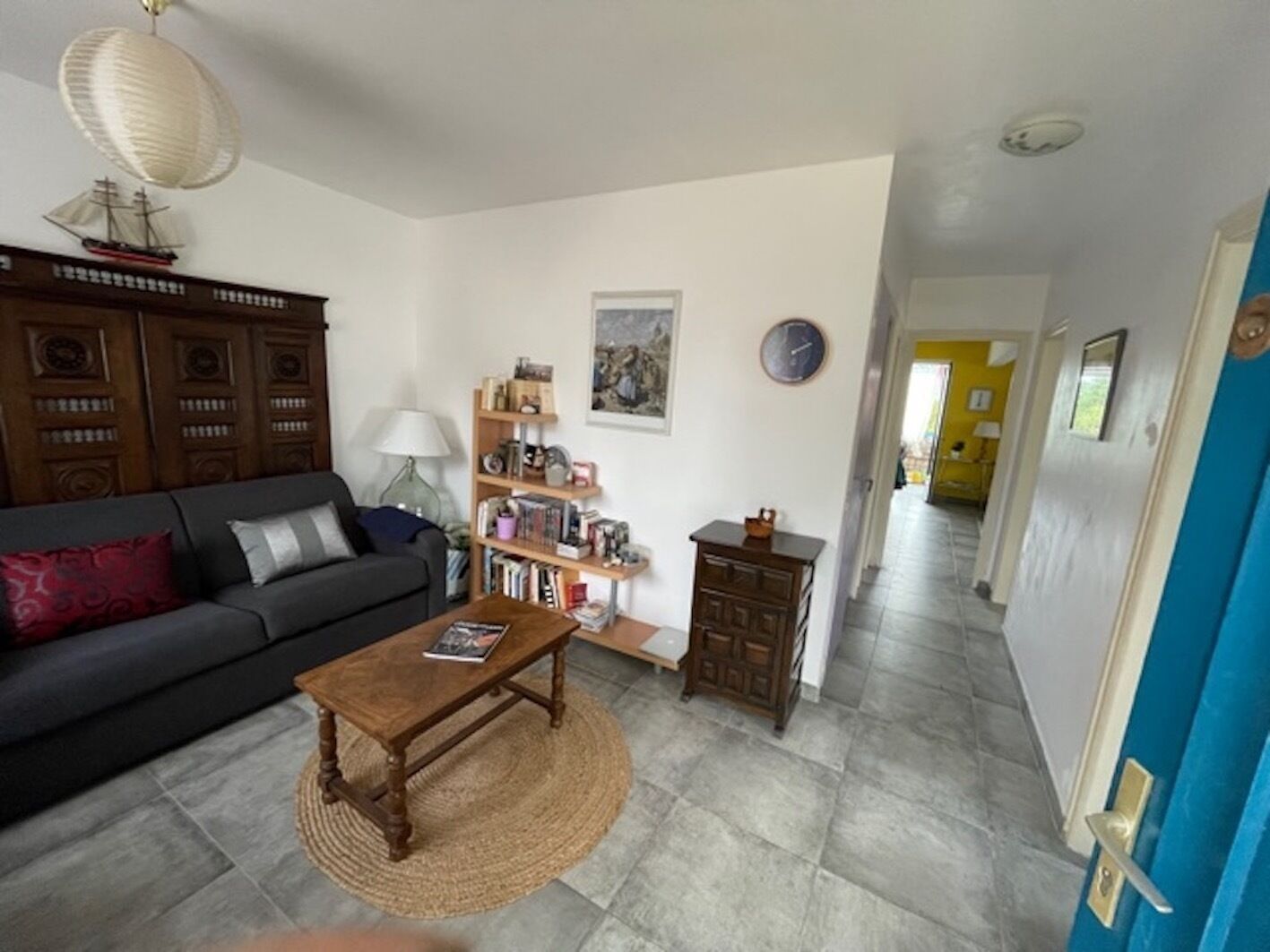 A living room with a sofa, coffee table, bookshelf, and a clock on the wall.