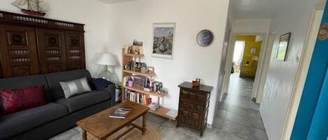 A living room with a sofa, coffee table, bookshelf, and a clock on the wall.