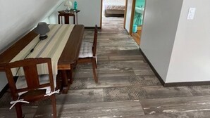 Un couloir étroit avec un plafond en pente, un plancher en bois et un coin repas comprenant une table et des chaises.