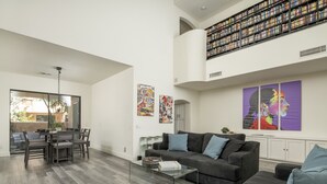 A spacious living room with a dining area, a large bookshelf, and artwork on the walls. - Modern Spacious 2 Master Bedroom Cal King with Loft & Pool Sleeps 6 (Chandler)
