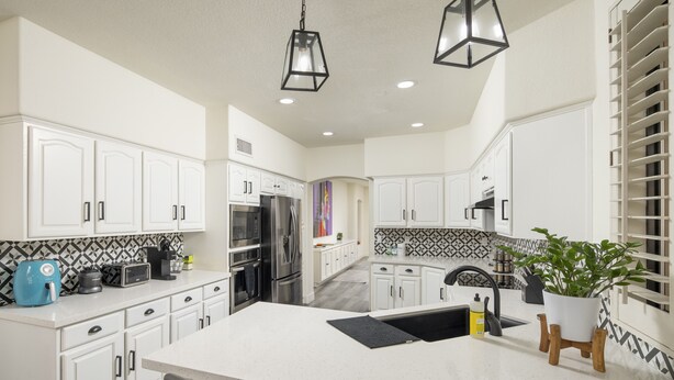 A modern kitchen with white cabinetry, a central island, and a black countertop. - Modern Spacious 2 Master Bedroom Cal King with Loft & Pool Sleeps 6 (Chandler)