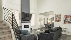 A spacious living area with a staircase, grey sofas, a glass coffee table, and artwork on the walls. - Modern Spacious 2 Master Bedroom Cal King with Loft & Pool Sleeps 6 (Chandler)