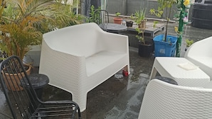 A covered outdoor seating area with wicker furniture, potted plants, and a water feature. - Luxurious Apartment 4to level with security camera (Santo Domingo Norte)