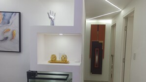 A modern interior with a white console table displaying a fish tank, decorative items, and a vase. - Luxurious Apartment 4to level with security camera (Santo Domingo Norte)