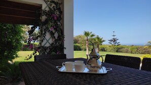 Un área de comedor al aire libre con una mesa preparada para dos personas, que incluye una bandeja con tazas y una tetera.