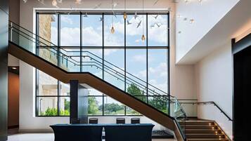 Un interior moderno con una escalera de cristal, ventanas amplias y un diseño minimalista.
