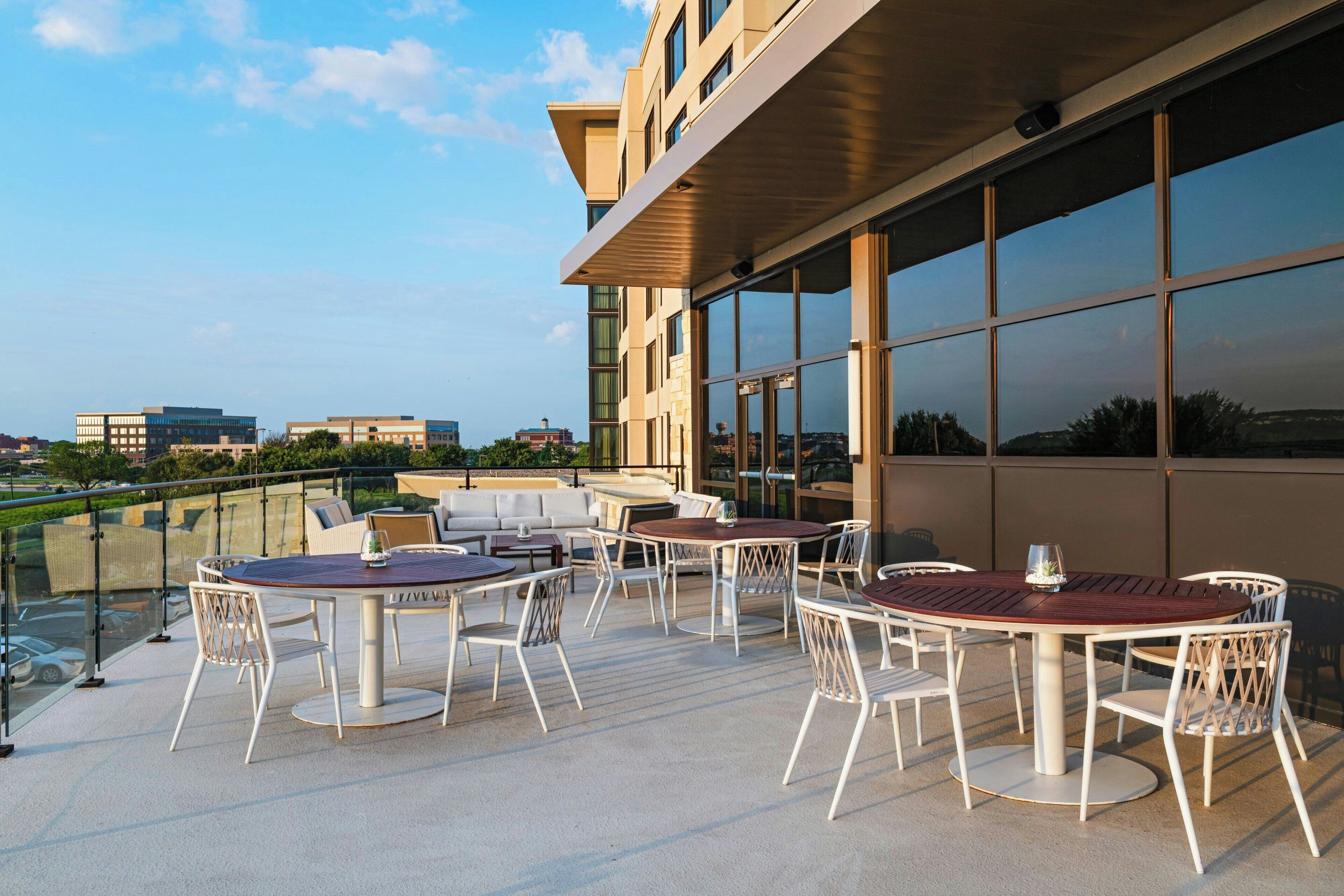 Terraço no telhado com área de estar ao ar livre e grandes janelas que oferecem vistas da paisagem urbana.