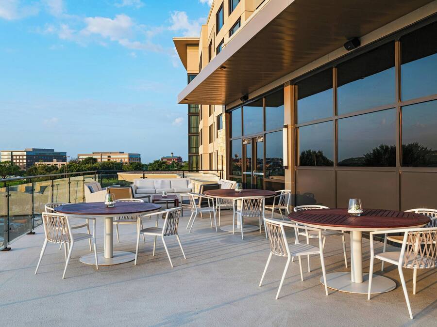 Terraço no telhado com área de estar ao ar livre e grandes janelas que oferecem vistas da paisagem urbana.