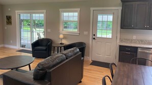 A spacious living area with a sofa, a dining table, and a kitchen with dark cabinets. - Riverside Escape - Riverfront Home on 1 acre (Hanover Township)