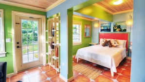 A bedroom with a bed, a door, a window, and a wall with a painting.