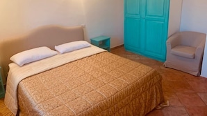 Un dormitorio con cama, mesita de noche, armario azul turquesa y una silla.