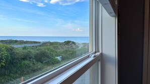 Una ventana con vista al océano y una carretera que lleva a la playa.