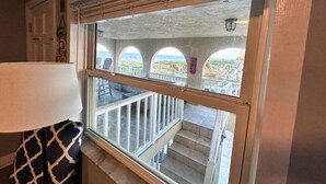 Una habitación con un ventanal grande que da a un balcón con vistas al océano y un edificio con arcos.