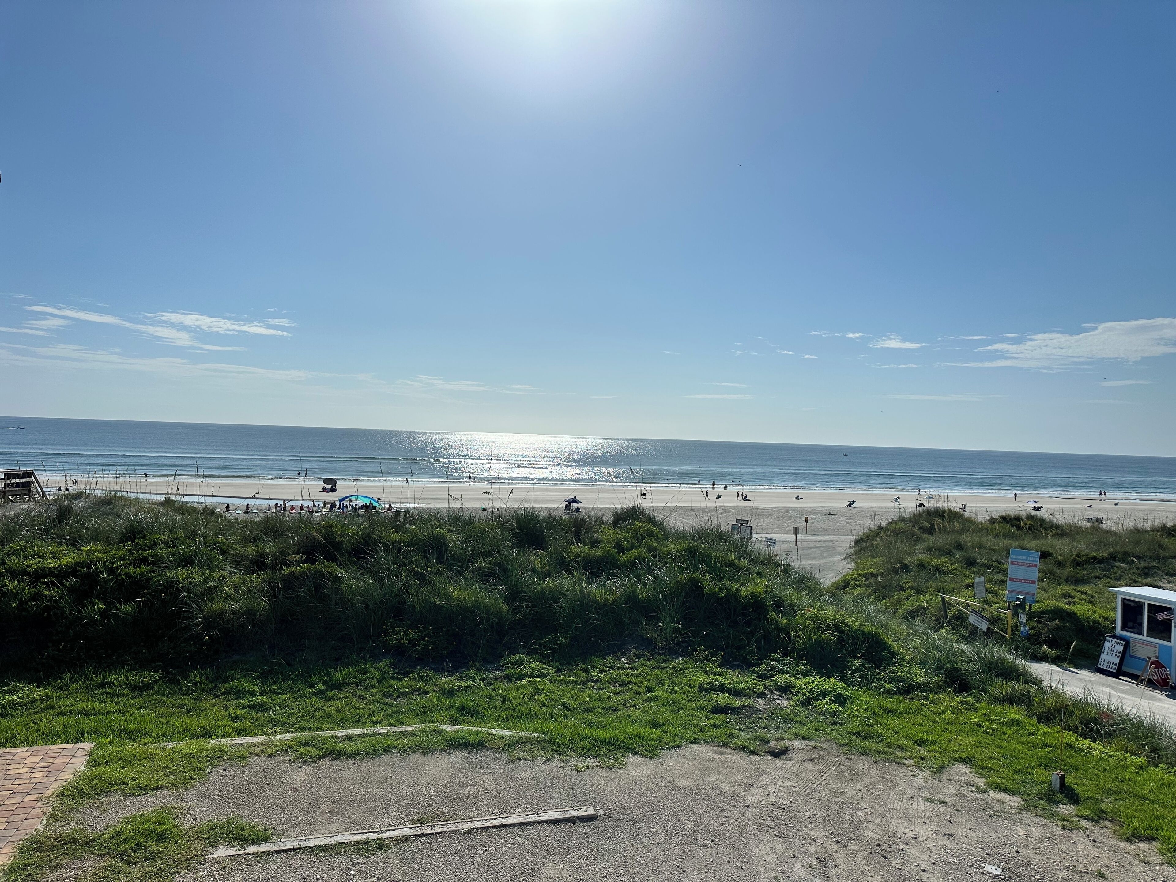 A beach with a clear sky, a lifeguard tower, and a signboard.