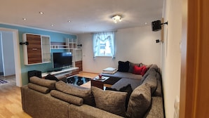 Una sala de estar moderna con un sofá grande, un televisor de pantalla plana y estanterías empotradas.