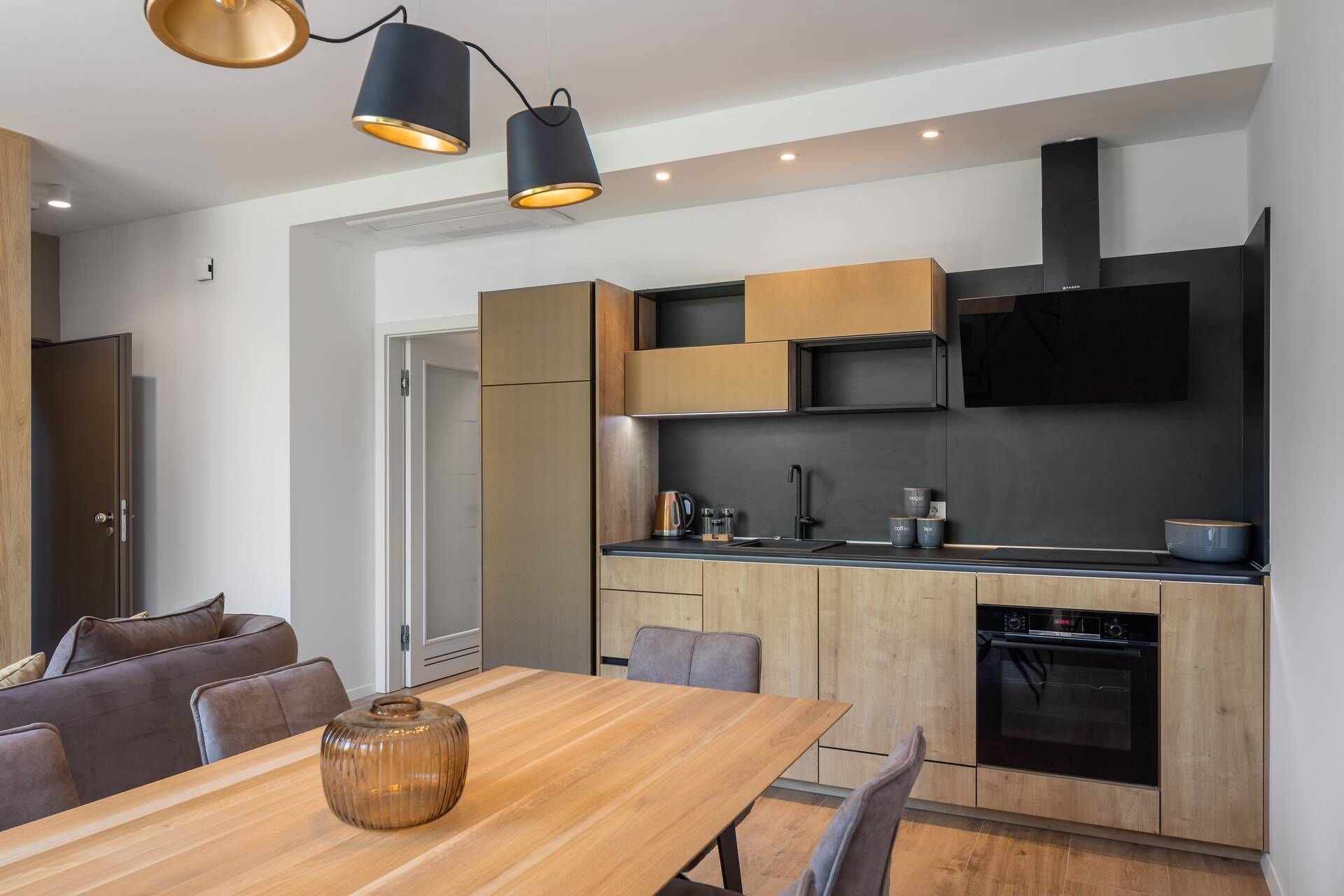 Eine moderne Küche mit Holdekor, Backofen und Essbereich mit Holztisch und Stühlen.
