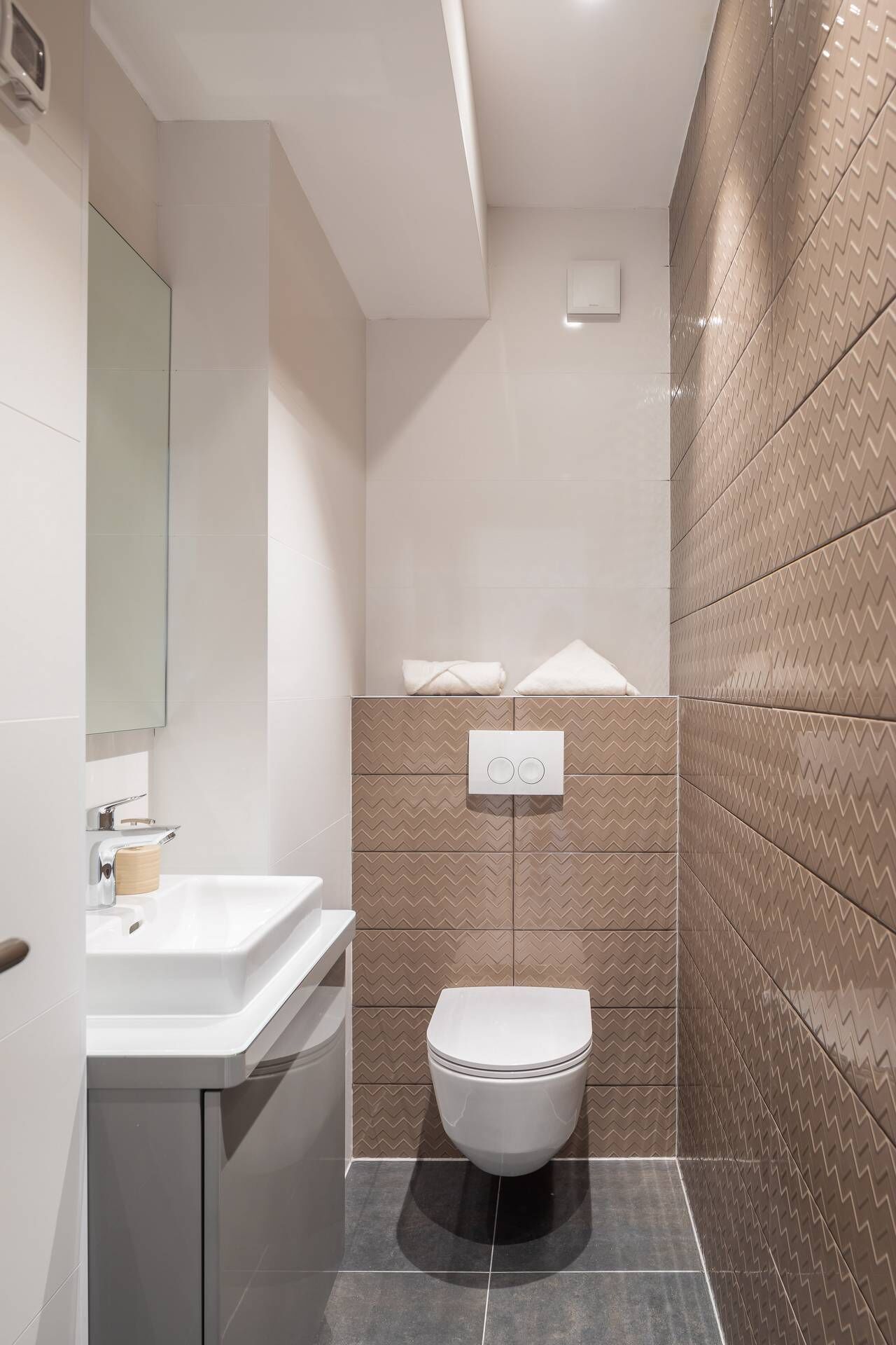 A modern bathroom with a white sink, a toilet, and a shower area.
