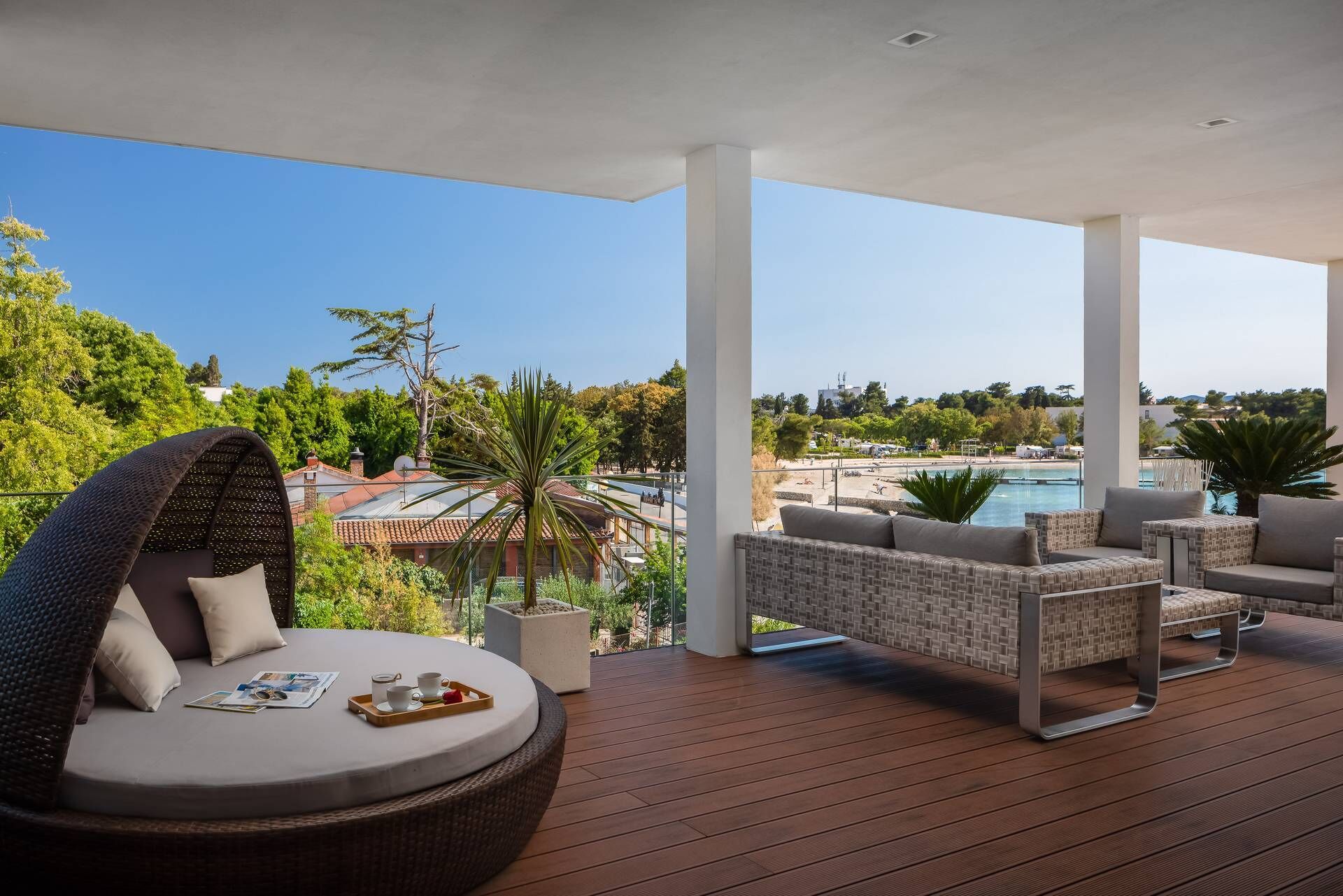 A covered outdoor seating area with wicker furniture, a pool, and a view of the surrounding landscape.