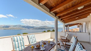 Una terraza con mesa de madera lista para el desayuno, con vista a un lago y montañas.