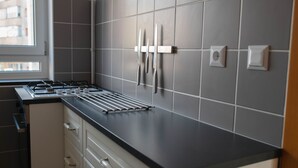 Cozinha moderna com bancada preta, armários brancos e janela que proporciona iluminação natural.
