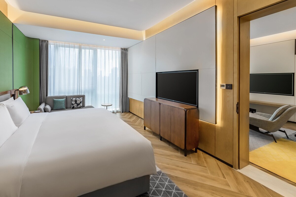 Een hotelkamer met een groot bed, een televisie, een bureau en een stoel.