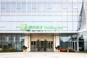 Un bâtiment moderne, avec une enseigne Holiday Inn, de grandes fenêtres en verre et un hall d’entrée bien entretenu.