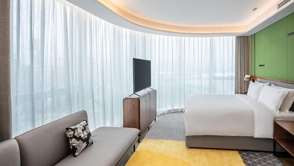 A modern hotel room with a large bed, a sofa, a flat-screen TV, and a green accent wall. - Holiday Inn Xi An Chanba (Xi'an)