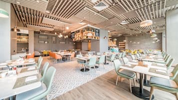 A modern restaurant interior with a variety of seating arrangements, including tables and booths, and a patterned floor.