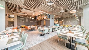 A modern restaurant interior with a variety of seating arrangements, including tables and booths, and a patterned floor. - Holiday Inn Xi An Chanba (Xi'an)