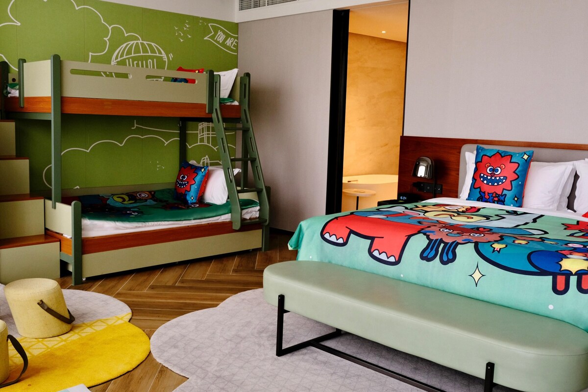 Een stapelbed met een groene muur, een tafeltje en een bank.