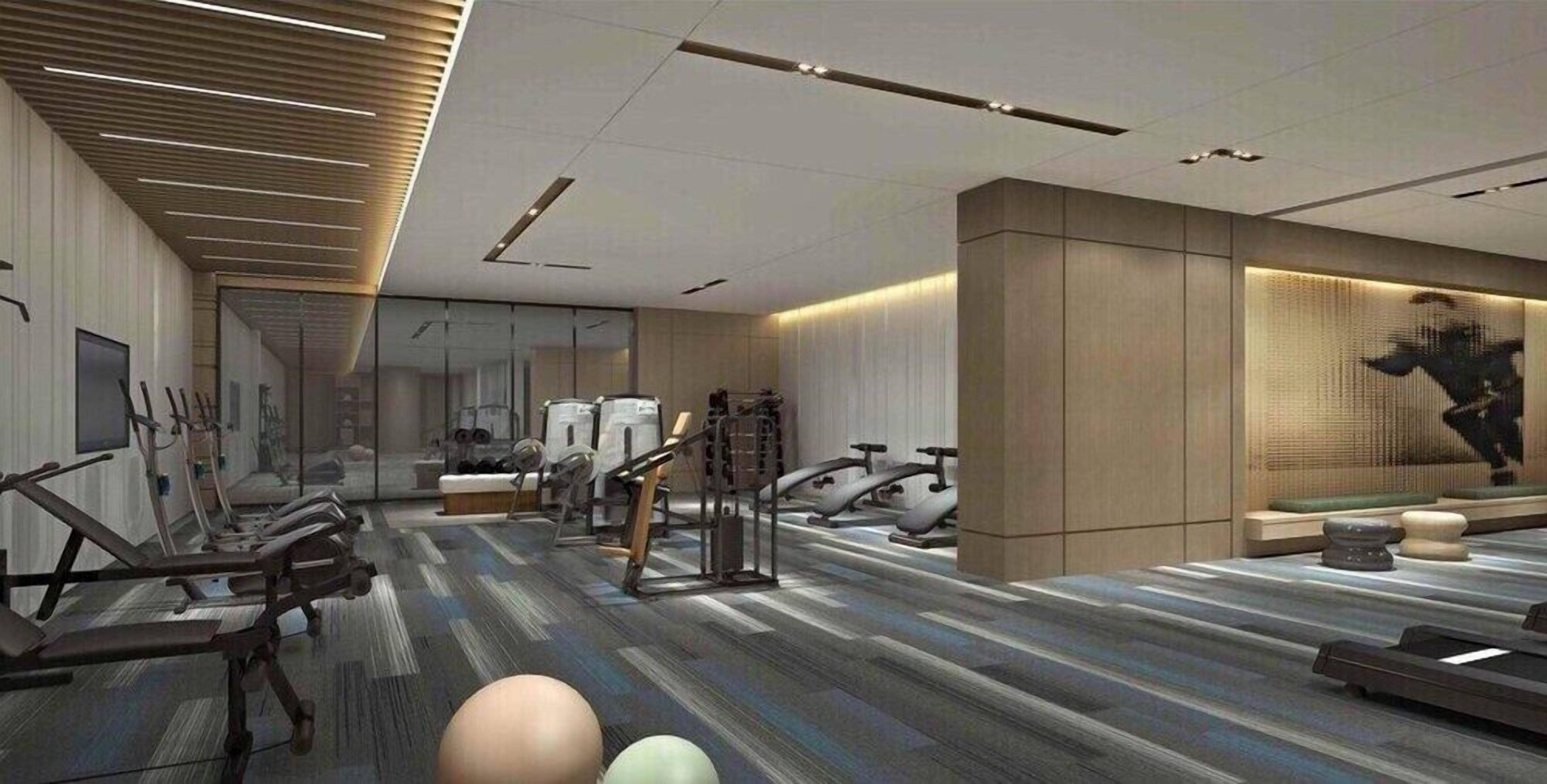 A modern gym with exercise equipment, a patterned carpet, and a large mirror.