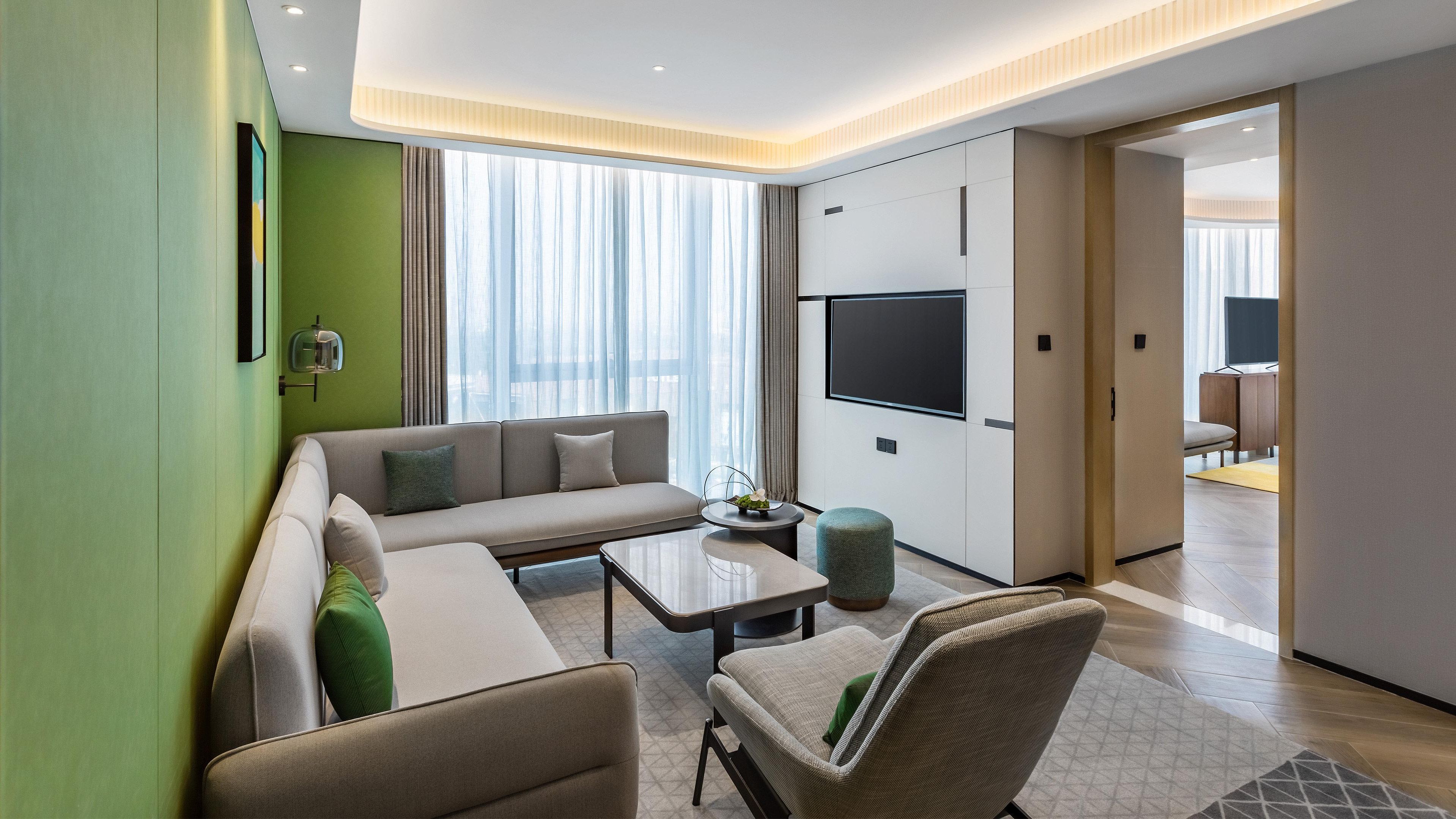 A modern living room with a sofa, armchairs, a coffee table, and a TV.