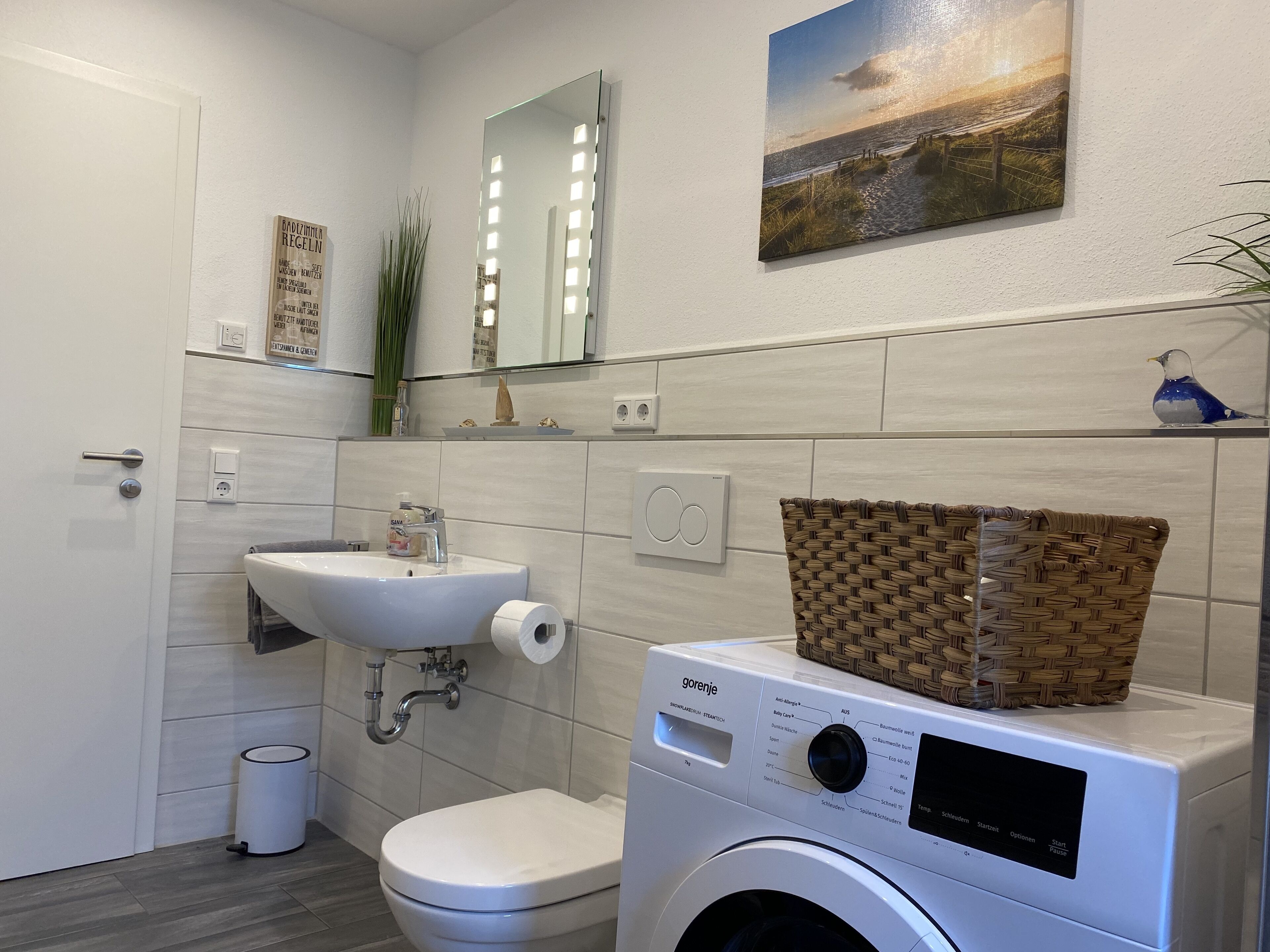 Un bagno moderno con il water, un lavandino e una lavatrice.
