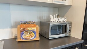 Uma bancada de cozinha com micro-ondas e um cartaz de boas-vindas.