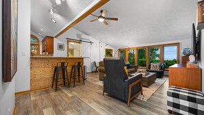 A spacious living area with a kitchen, wooden flooring, and large windows offering natural light. - 2 Bedroom Carriage House with view of Suttons Bay (Suttons Bay)