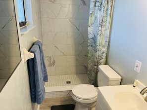 A bathroom with a toilet, sink, and shower area. - 2,2 Stilted House on private peninsula. Renovated June '23.  (Homosassa)
