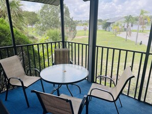 A covered outdoor area with a round table and four chairs, surrounded by a blue carpet and metal railings. - 2,2 Stilted House on private peninsula. Renovated June '23.  (Homosassa)