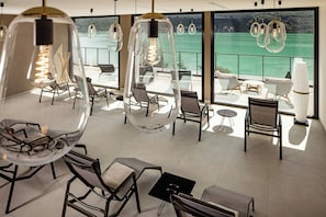 Un espace de détente moderne avec des suspensions en verre transparent, des sièges confortables et une vue sur la mer.