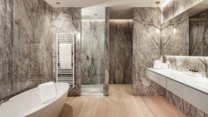 A modern bathroom with a freestanding bathtub, marble walls, and a large mirror.
