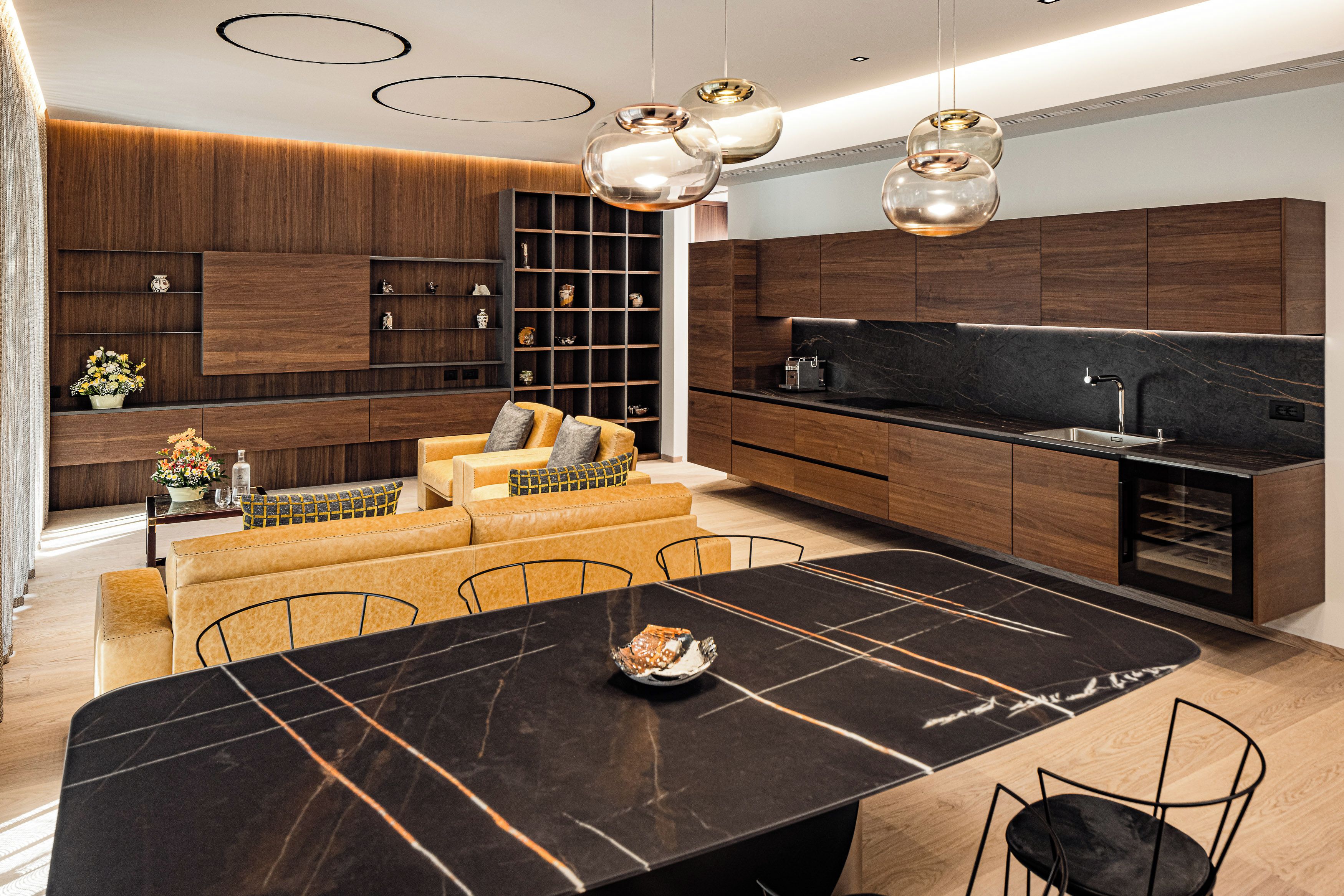 A modern kitchen with a black marble countertop, wooden cabinets, and a built-in oven.