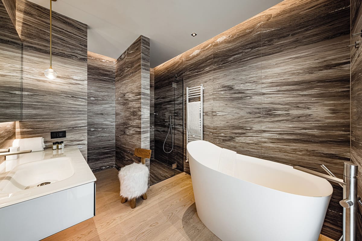 Une salle de bain moderne avec une baignoire sur pieds, une douche en verre et un mur à l’aspect marbré.