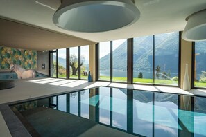 A modern interior with a glass-bottomed pool, large windows with a mountain view, and a minimalist design.